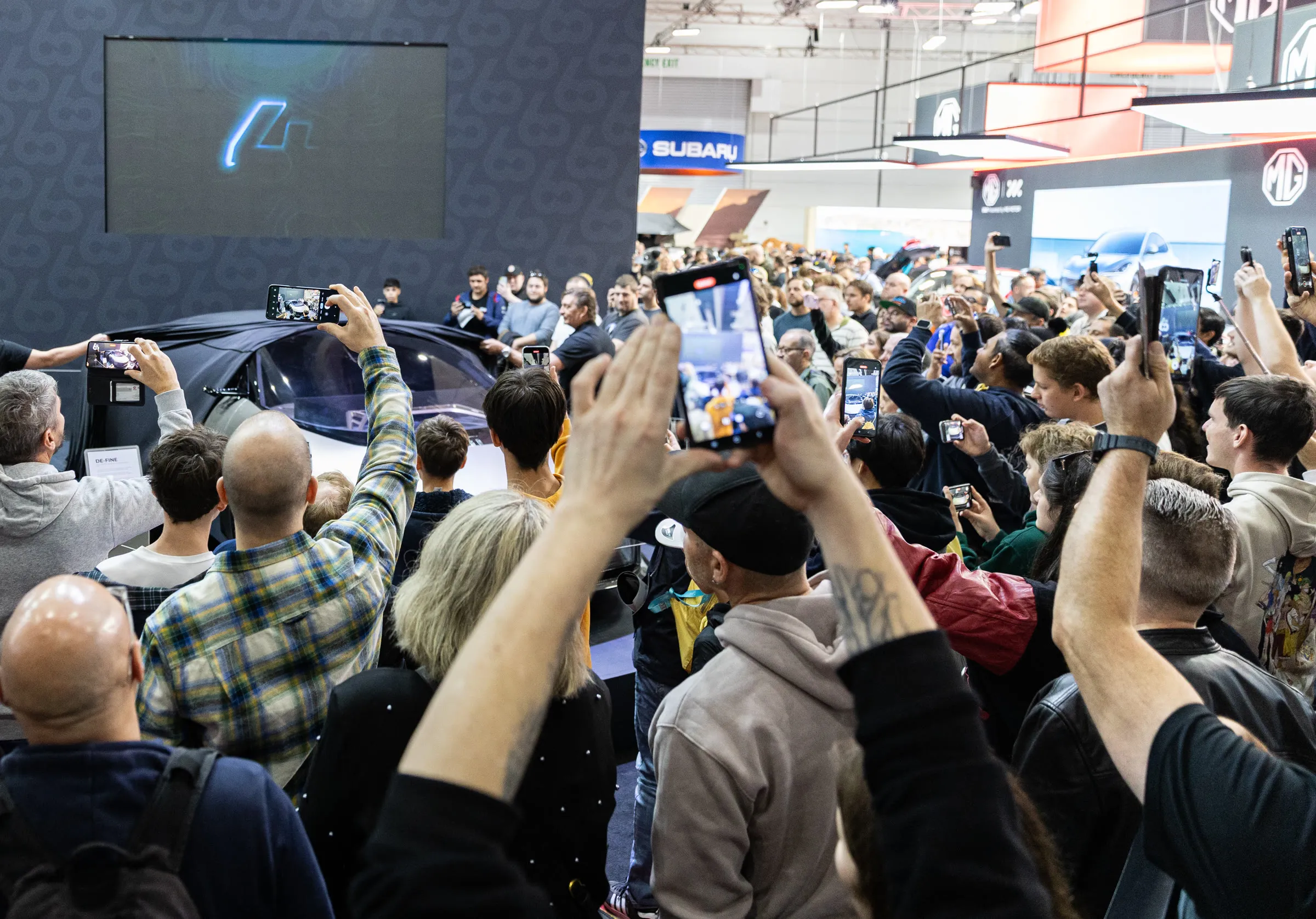 A crowd of delegates raising their phones to film a launch moment on stage